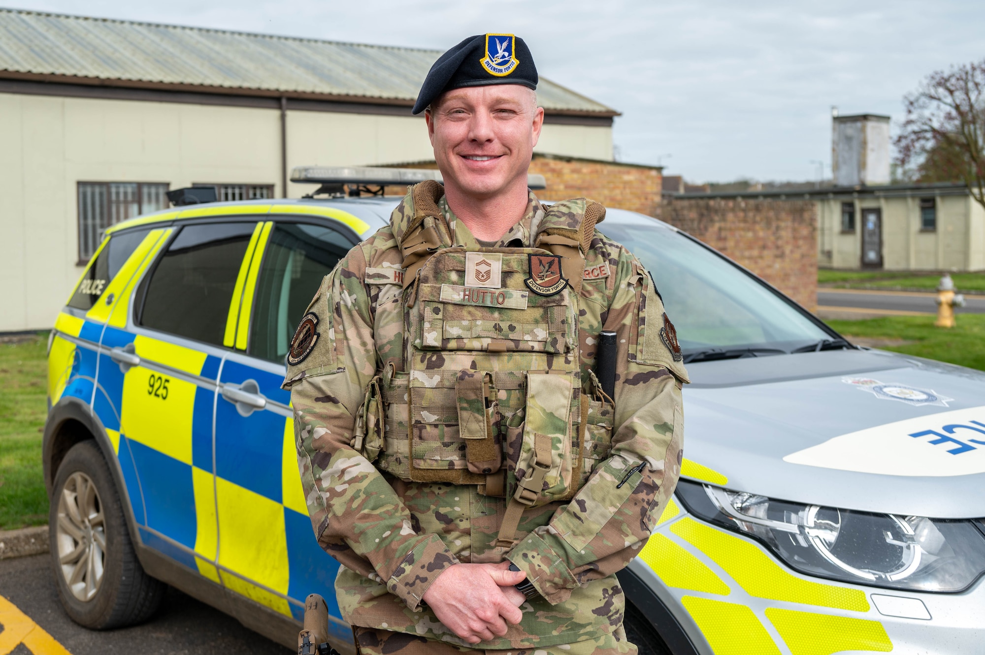 An Airman smiles for a photo outside of a British police car