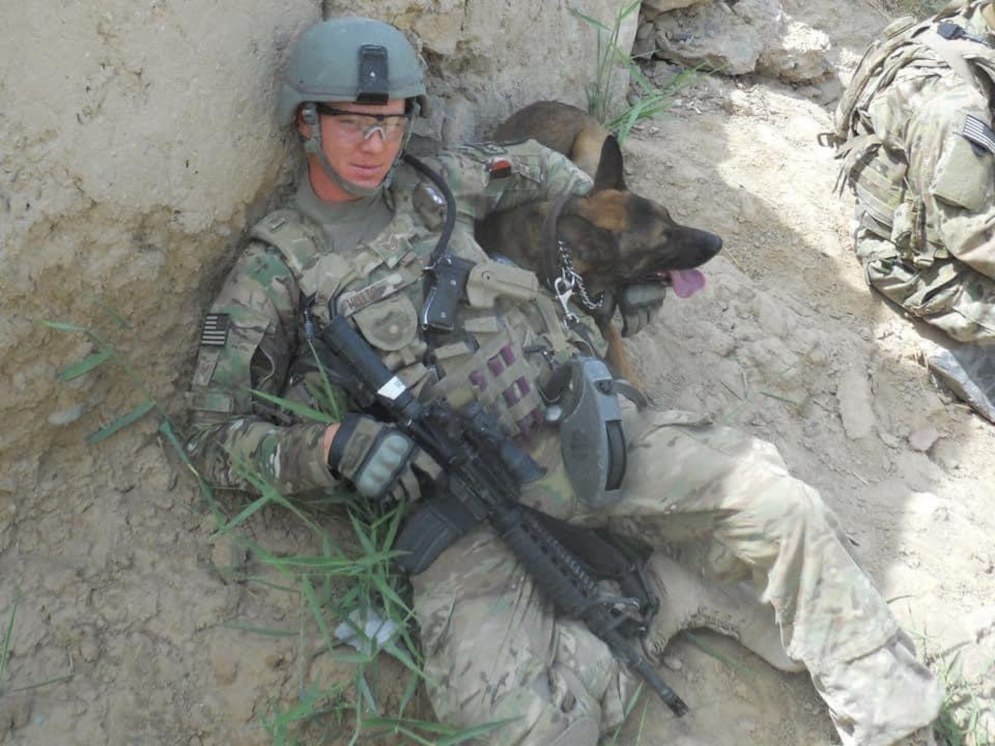 An Airman lays next to a military working dog