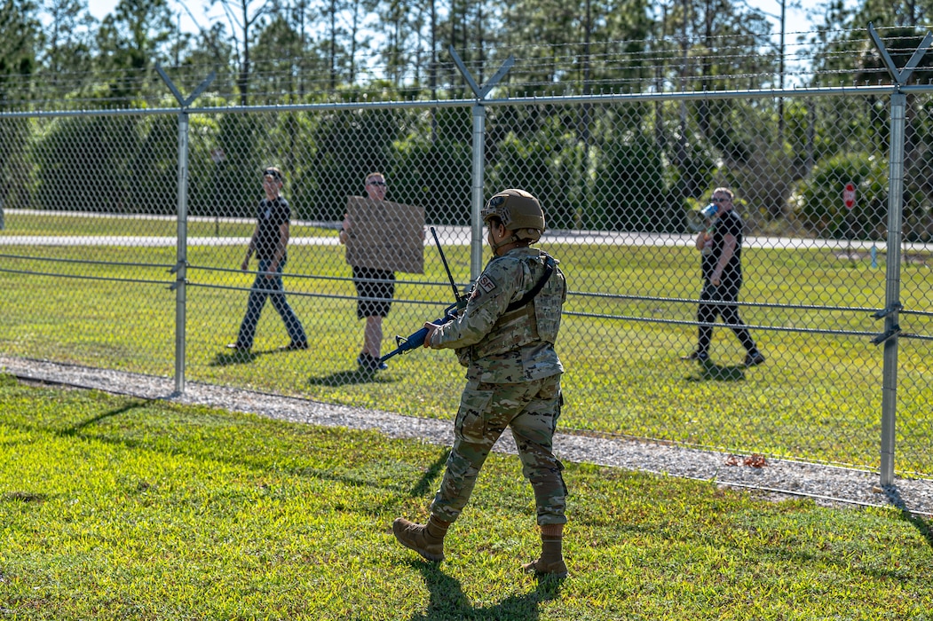 A U.S. Air Force Airman assigned to the 23rd Security Forces squadron patrols the fence while the 23rd Wing inspection team simulates a protest during Exercise Ready Tiger 24-1 at Avon Park Air Force Range, Florida, April 12, 2024. The simulated protest was an exercise scenario that tested Airmen’s preparedness and ability to respond to potential threats. Ready Tiger 24-1 is a readiness exercise demonstrating the 23rd Wing’s ability to plan, prepare and execute operations and maintenance to project air power in contested and dispersed locations, defending the United States’ interests and allies. (U.S. Air Force photo by Airman 1st Class Leonid Soubbotine)