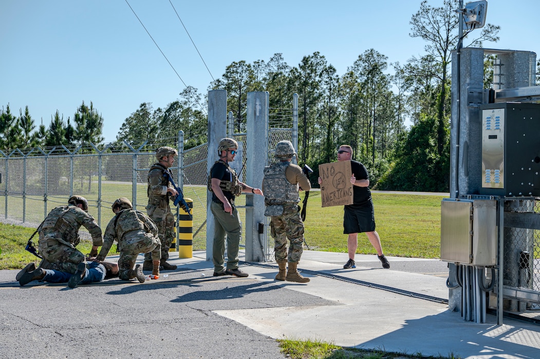 U.S. Air Force Airmen assigned to the 23rd Security Forces Squadron detain an intruder as the 23rd Wing inspection team members act as protestors during Exercise Ready Tiger 24-1 at Avon Park Air Force Range, Florida, April 12, 2024. The simulated unauthorized base entry tested Airmen’s ability to appropriately respond to a potentially dangerous situation. Ready Tiger 24-1 is a readiness exercise demonstrating the 23rd Wing’s ability to plan, prepare and execute operations and maintenance to project air power in contested and dispersed locations, defending the United States’ interests and allies. (U.S. Air Force photo by Airman 1st Class Leonid Soubbotine)