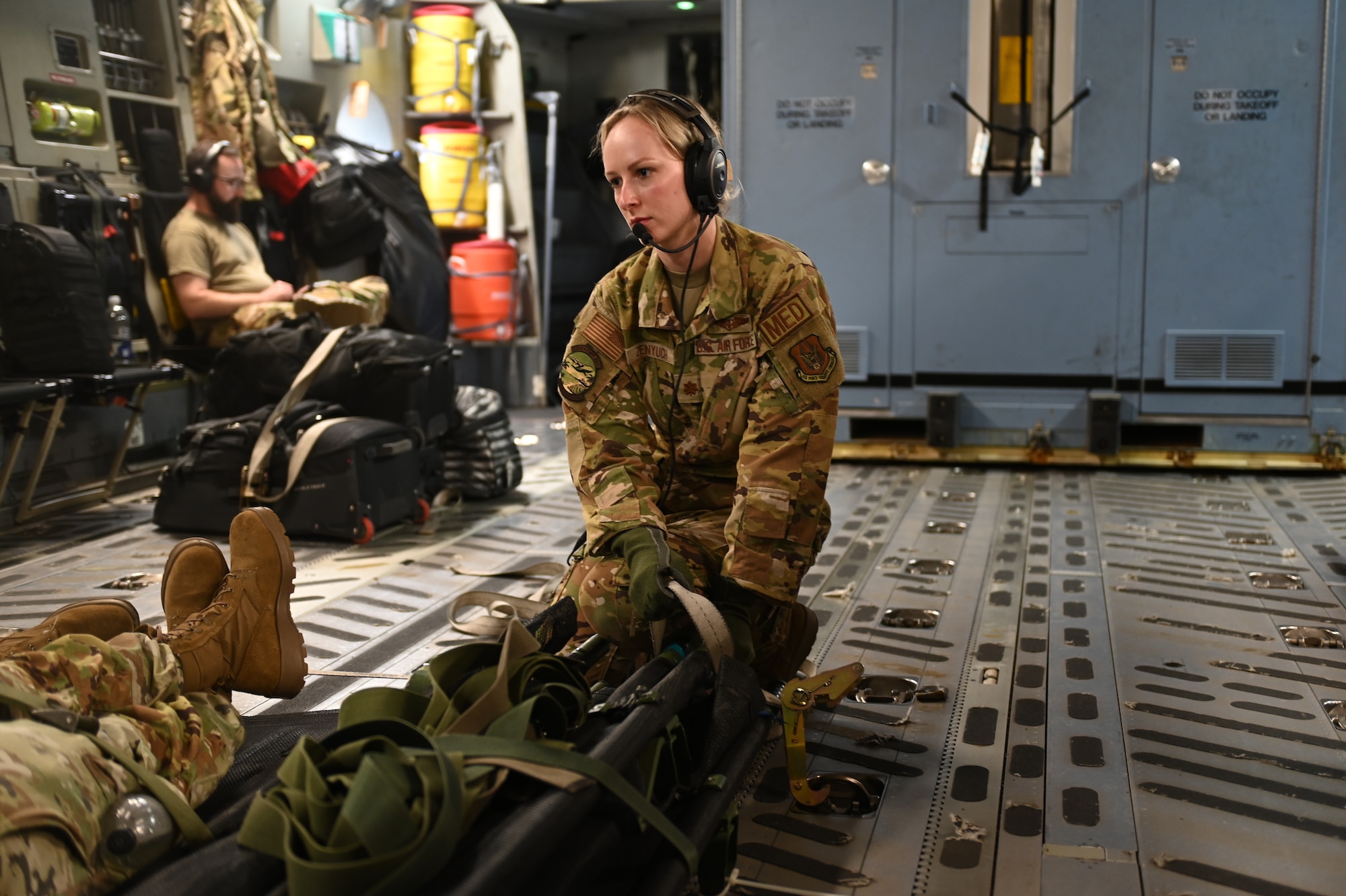 A U.S. Air Force flight nurse kneels by a patient litter on a C-17 Globemaster aircraft during exercise Conch Fury 2024 in April.