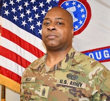 man wearing army uniform standing in front of two flags