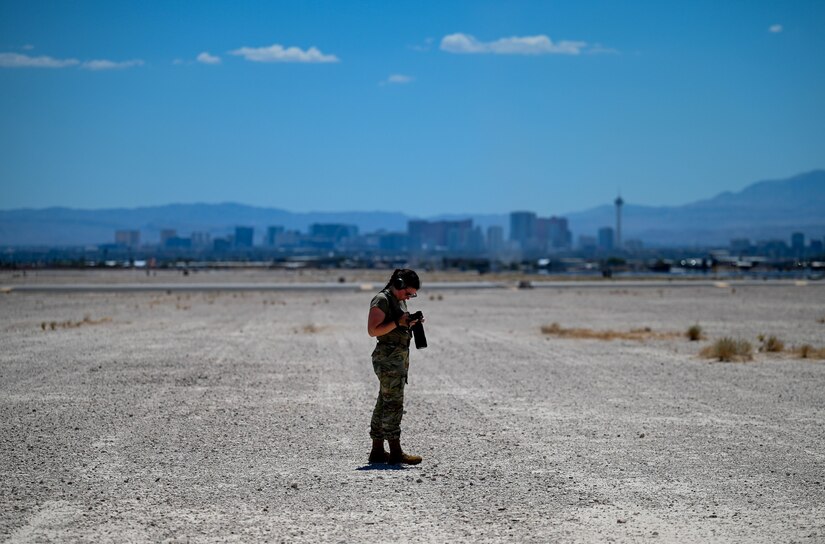 USAF Photographer looks through her collected imagery standing on a desert field