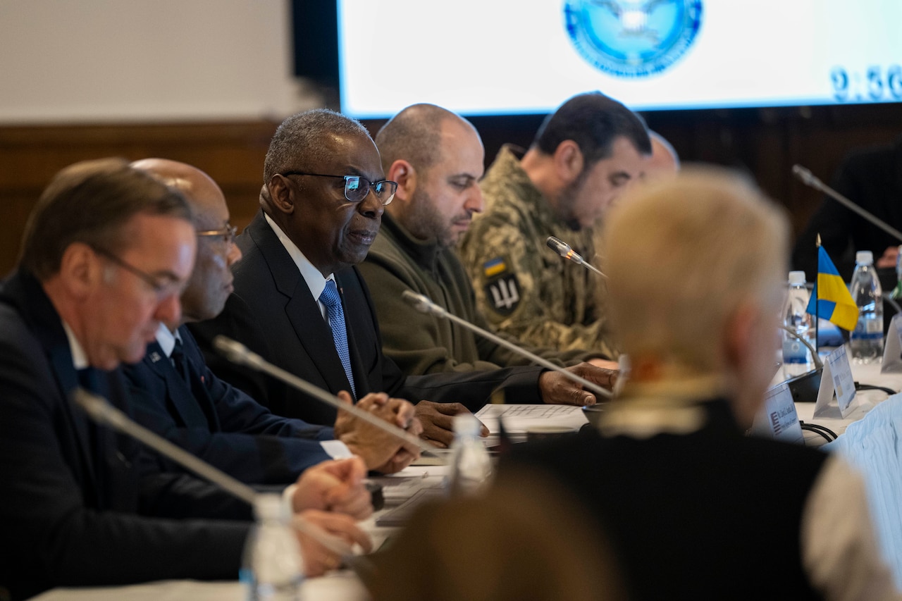 People wearing civilian attire and foreign military uniforms are seated at a table.