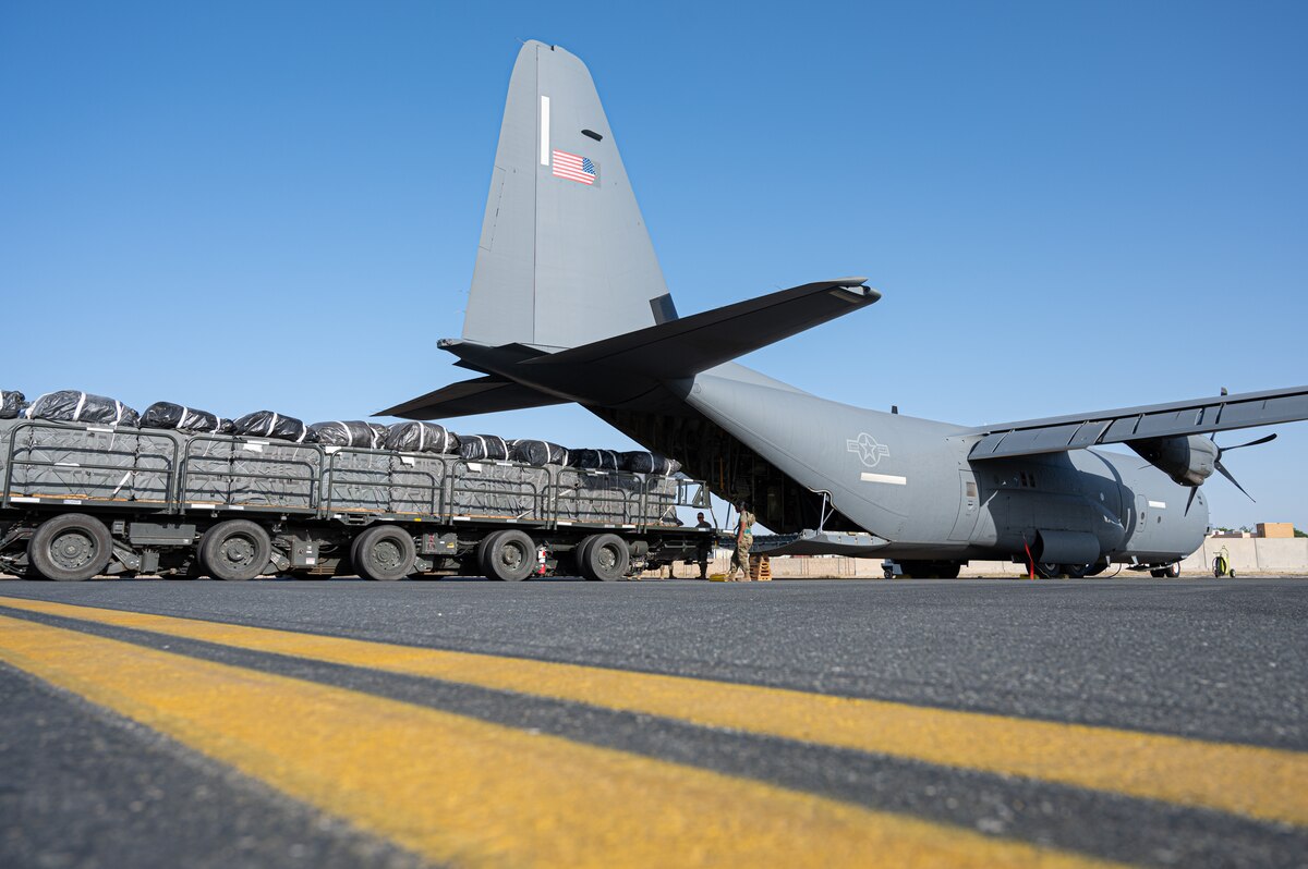Pallets are staged at the ramp of a military cargo plane.