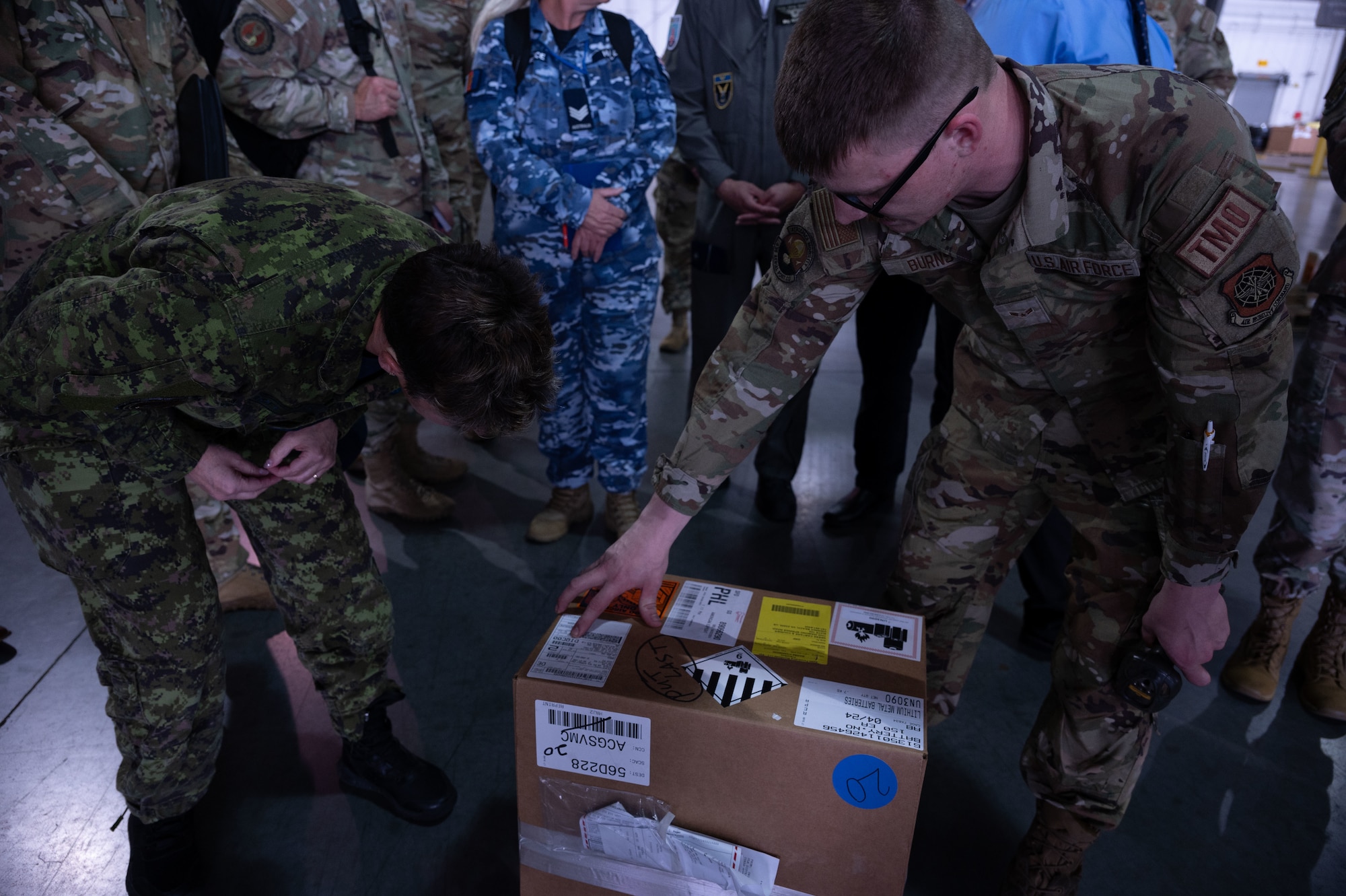 Royal Canadian Air Force Lt. Col. Lucie Croft, left, and U.S. Air Force Senior Airman Kevin Burns, 436th Aerial Port Squadron cargo processor, review a package label during a Foreign Liaison Officer visit at Dover Air Force Base, Delaware, April 23, 2024. This visit gave the Foreign Liaison Officers a chance to learn about Dover AFB's ongoing mission of rapid global mobility, and their nation’s role in foreign military sales missions.