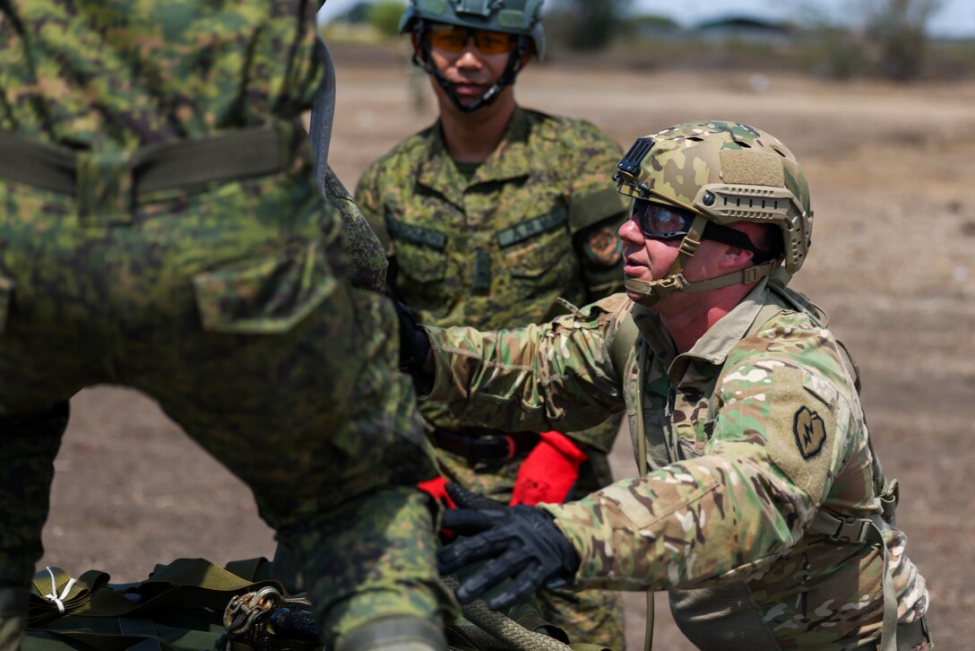 U.S. Army Warrant Officer Trevor Colcasure assigned to the 25th Infantry Division Sustainment Brigade, 25th Infantry Division, alongside Philippine Army Soldiers assigned to 7th Service Support Battalion, Army Support Command, and Special Forces Regiment Airborne conduct sling load training with a CH-47 Chinook helicopter from the 25th Combat Aviation Brigade, 25th Infantry Division with A22 cargo bags during a training mission in support of Exercise Balikatan 24 at Fort Magsaysay, Philippines, April 22, 2024. BK 24 is an annual exercise between the Armed Forces of the Philippines and the U.S. military designed to strengthen bilateral interoperability, capabilities, trust, and cooperation built over decades of shared experiences. (U.S. Army Photo by Spc. Kai Rodriguez, 28th Public Affairs Detachment)