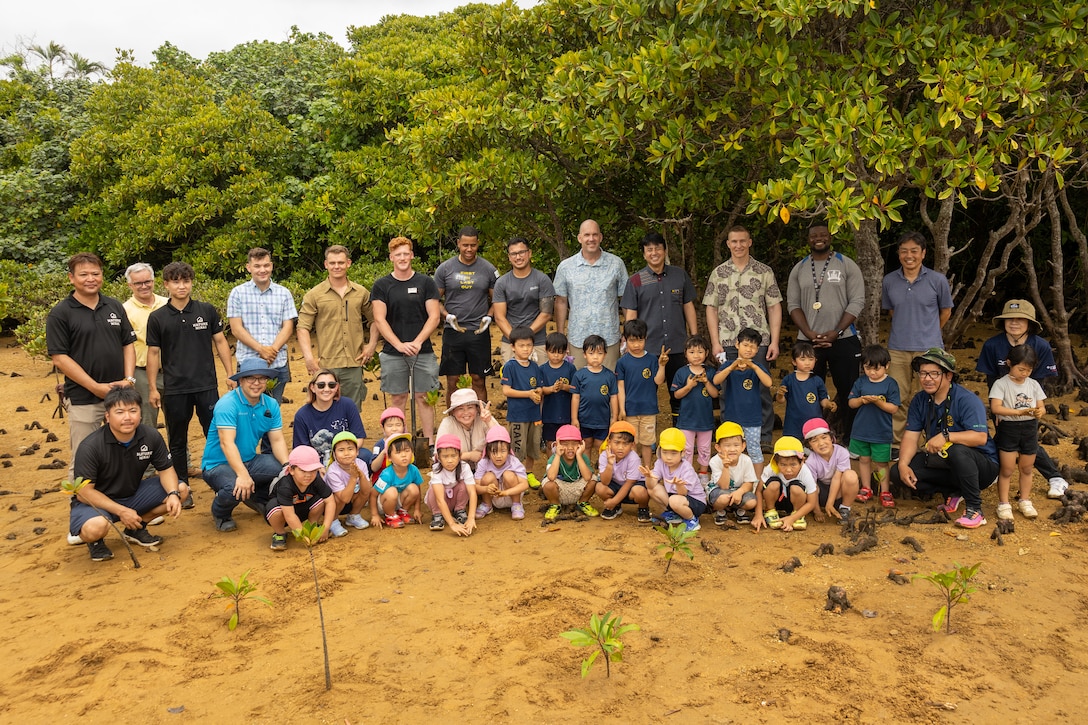 U.S. service members and local preschool students and staff members pose for a group photo after an Earth Day cleanup and tree-planting event at Nature Mirai Kan in Kin Town, Okinawa, Japan, April 22, 2024. Marine Corps Installations Pacific coordinated a week of Earth Day events to reinforce relationships between U.S. service members and the Okinawa community. The participants planted a total of 32 mangrove trees. (U.S. Marine Corps photo by Sgt. Maximiliano Rosas)