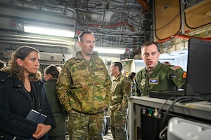 Maj. Christian Brechbuhl, right, Air Mobility Command mission systems deputy director, demonstrates the Airlift Tanker Open Mission Systems program to senior leaders on a C-17 Globemaster III April 24, 2024, on the flightline at Ramstein Air Base, Germany.