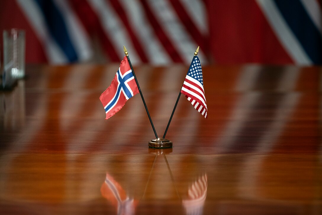 The U.S. and Norway flags are displayed on a wooden table.