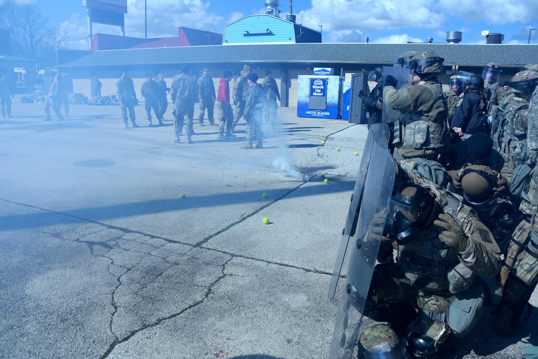 A smoke canister is discharged as members of the Wisconsin Army National Guard’s 157th Maneuver Enhancement Brigade and Milwaukee-area law enforcement find themselves between two belligerent groups of demonstrators during an April 5 training exercise at the Wisconsin State Fairgrounds in West Allis. Soldiers took turns training in a reaction force role in support of local law enforcement as well as portraying looters and rioters. This type of training addresses communication skills between agencies and improves understanding and collaboration between local law enforcement and the Wisconsin National Guard. Wisconsin Department of Military Affairs photo by Vaughn R. Larson