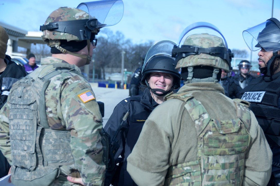 Members of the Wisconsin Army National Guard’s 157th Maneuver Enhancement Brigade and Milwaukee-area law enforcement coordinate their plans during an April 5 training exercise at the Wisconsin State Fairgrounds in West Allis. Soldiers took turns training in a reaction force role in support of local law enforcement as well as portraying looters and rioters. This type of training addresses communication skills between agencies and improves understanding and collaboration between local law enforcement and the Wisconsin National Guard. Wisconsin Department of Military Affairs photo by Vaughn R. Larson