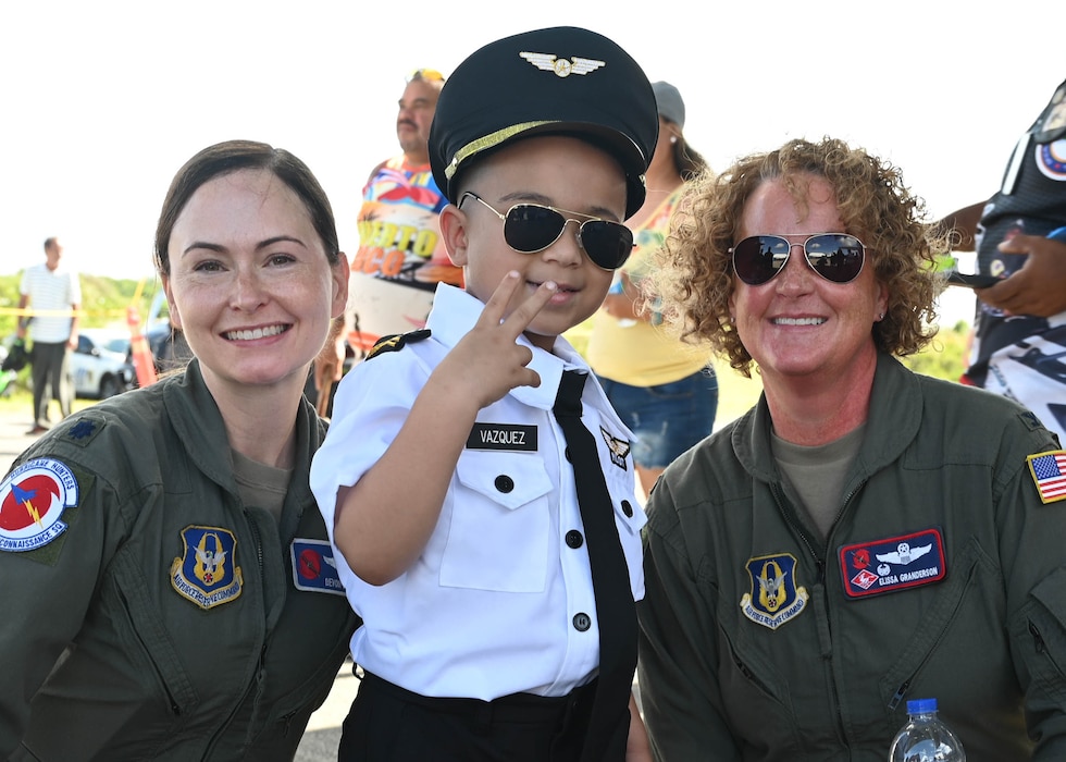Col. Elissa Granderson, 403rd Operations Group commander and pilot, and Lt. Col. Devon Burton, 53rd Weather Reconnaissance Squadron pilot, pose for a photo with one enthusiastic youth