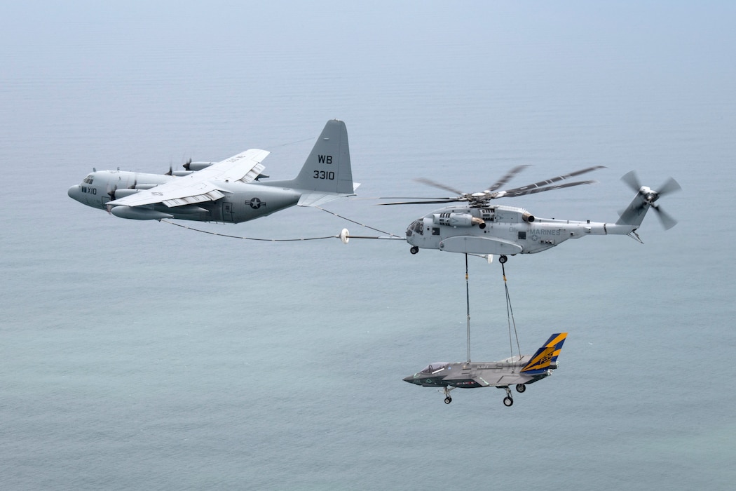 A USAF C-130 Hercules refuels a USMC CH-53K helicopter as it transports a Navy F-35C airframe.
