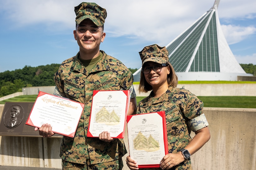 Two smiling uniformed service members pose holding certificates.