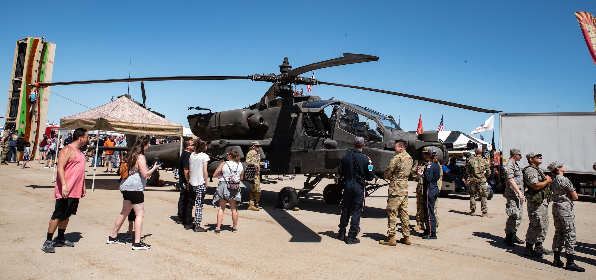 People standing around a military helicopter.