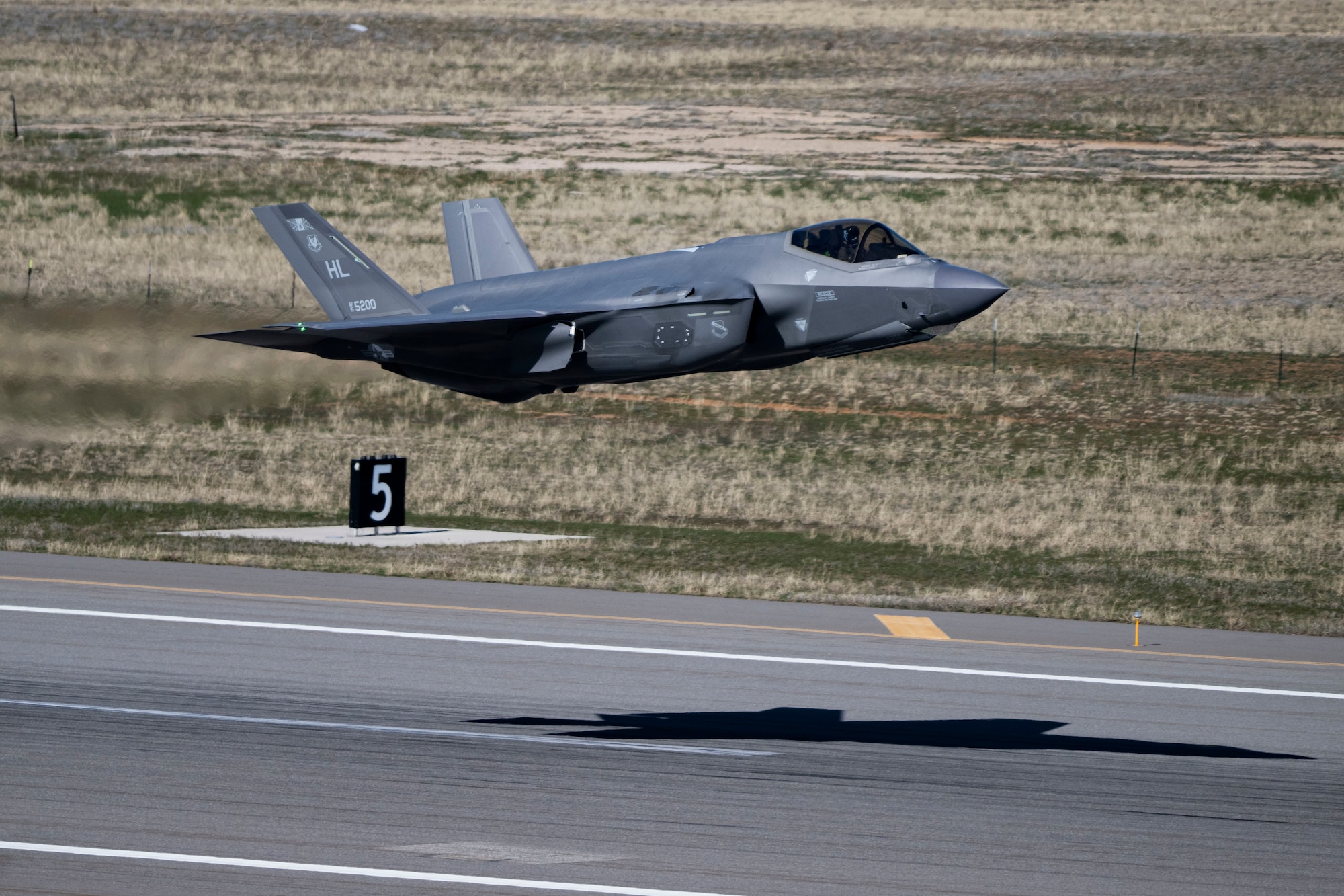 A military airplane flies a few feet off the runway