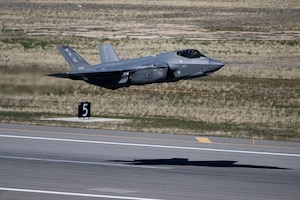 A military airplane flies a few feet off the runway