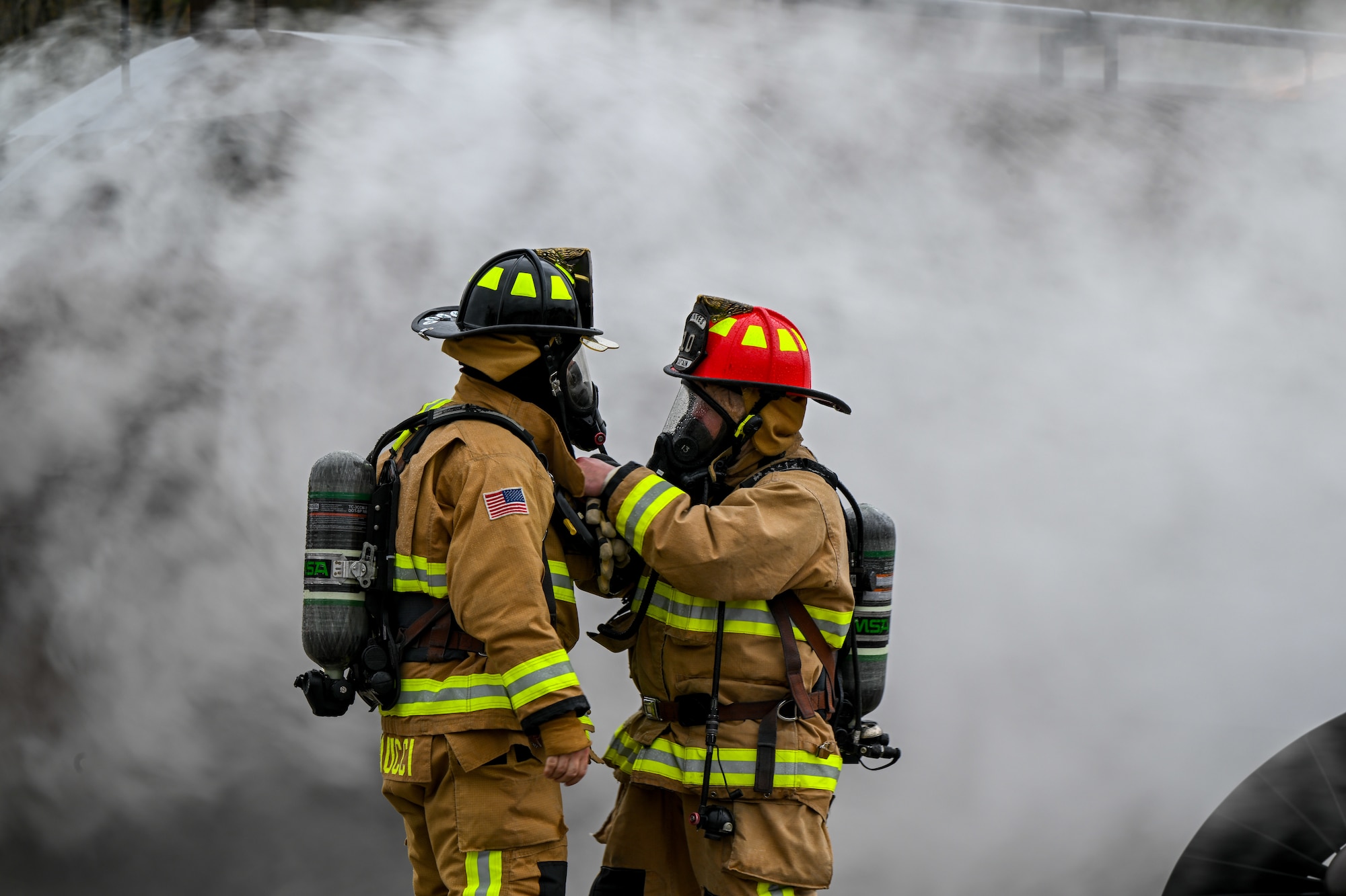 Youngstown Air Reserve Station fire captain John West helps firefighter Mike Sanducci adjust his gear while responding to a mock aircraft crash at the firefighter training area during an exercise at Youngstown Air Reserve Station, Ohio, April 25, 2024.