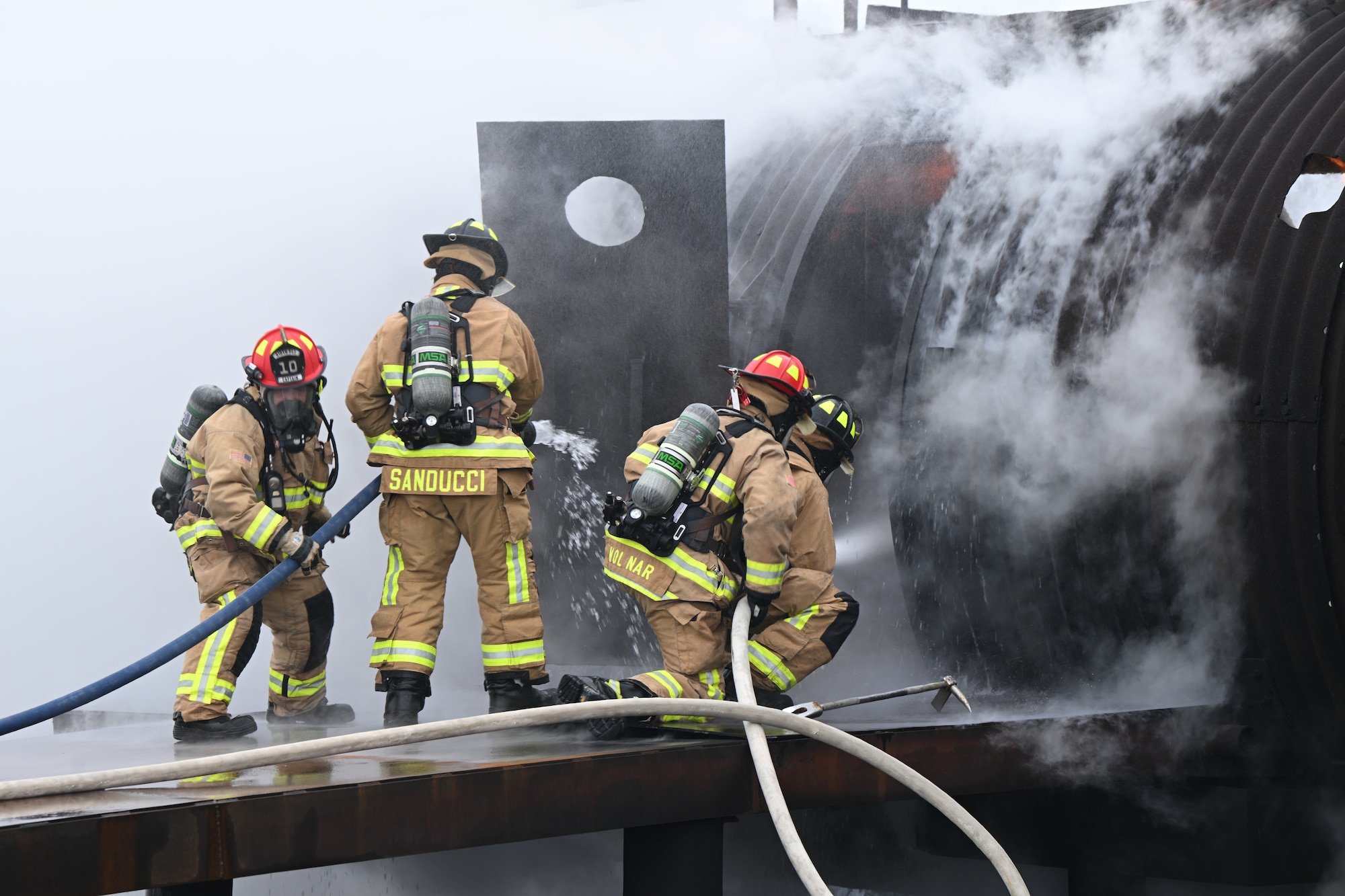 Youngstown Air Reserve Station firefighters spray water through the aircrew door while responding to a mock aircraft crash at the firefighter training area during an exercise at Youngstown Air Reserve Station, Ohio, April 25, 2024.