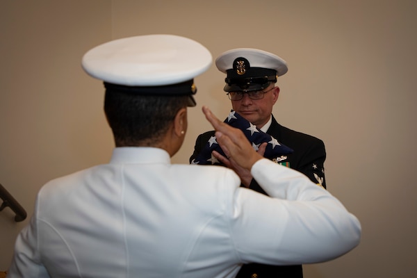 240419-N-KC192-2186 PORTSMOUTH, Va. (April 19, 2024) Strike Fighter Squadron 146 Command Master Chief Joselin Cruzdelossantos salutes an United States flag passed to Naval Medical Forces Atlantic Command Master Chief Zachary Pryor, a native of Alliance, Nebraska,  during Pryor's retirement ceremony on board Naval Support Activity (NSA) Hampton Roads - Portsmouth Annex, April 19, 2024. Pryor served the Navy for nearly 32 years of dedicated service across 13 commands. (U.S. Navy photo by Mass Communication Specialist 2nd Class Levi Decker)