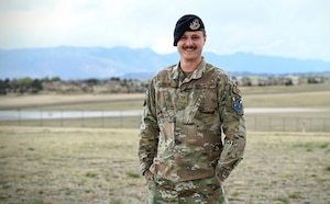 A defender stands in a field with mountain background for a portrait.