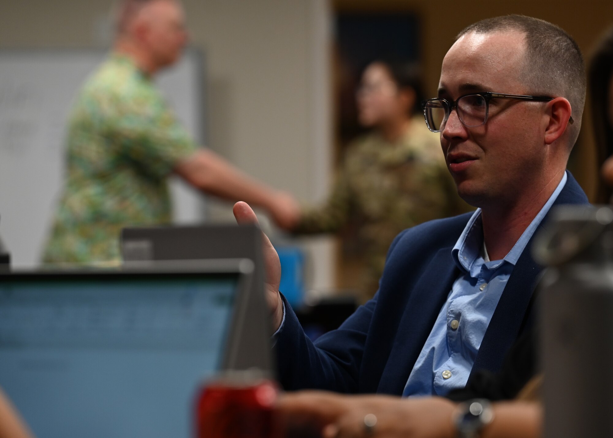 Man sits at a desk with computer and speaking.