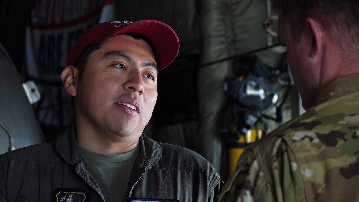 A photo of two U.S. Air National Airmen facing each other while talking in the back of a dimly lit C-130J Super Hercules equipped with the MAFFS unit.