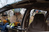 A photo of a firefighter cutting a car hood.
