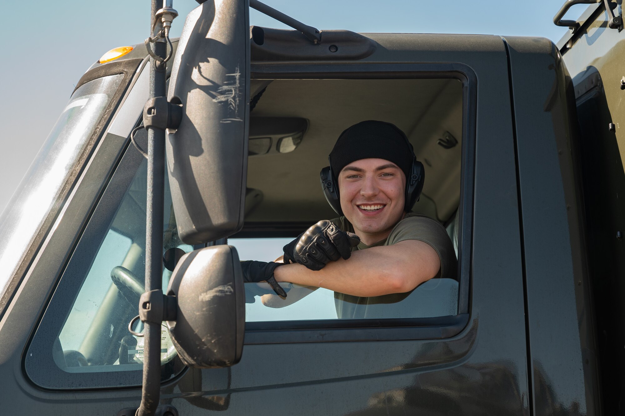 U.S. Air Force Airman 1st Class Victor Chamlee leans out the window of a truck.