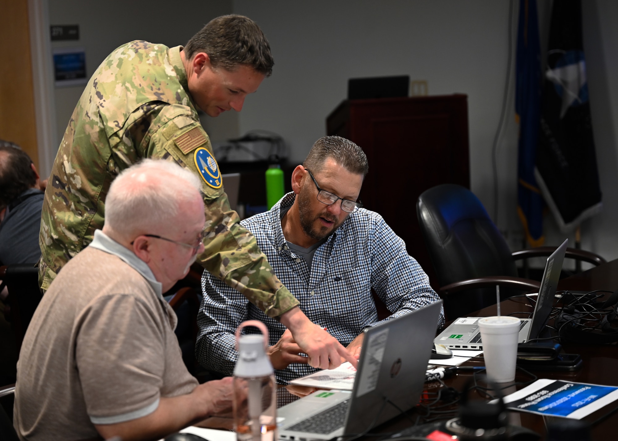 Team of three men look at a white sheet of paper.