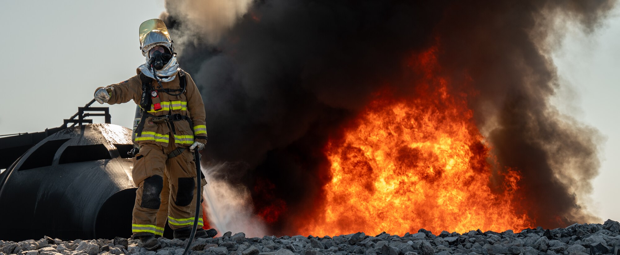 A firefighter stands in front of a fire
