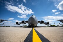 Front view of a C-17 on the flightline with blue skies and clouds