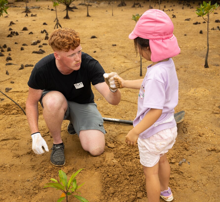 U.S. Marine Corps Lance Cpl. Blake Pruett, a mortarman with 3rd Battalion 2nd Marine Regiment, 2nd Marine Division, gives a local preschool student a fist-bump during a park clean up and tree planting event at Nature Mirai Kan in Kin Town, Okinawa, Japan, April 22, 2024. Marine Corps Installations Pacific coordinated a week of Earth Day events. The participants planted a total of 32 mangrove trees. Pruett is a native of Indiana. (U.S. Marine Corps photo by Sgt. Maximiliano Rosas)