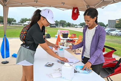 1st Lt. Zizi Zemeheret, 59th Medical Operations Squadron social work fellow, assists a participant in registering for an Alcohol Awareness Month 5K at Wilford Hall Ambulatory Surgical Center, Joint Base San Antonio-Lackland, Texas, April 27, 2024. The event, organized by the Alcohol and Drug Abuse Prevention and Treatment program, featured an interactive activity where they could wear drunk goggles and ride quadcycles simulating the effects of inebriation while driving to promote awareness and understanding of alcohol misuse. (Air Force photo by Senior Airman Melody Bordeaux)