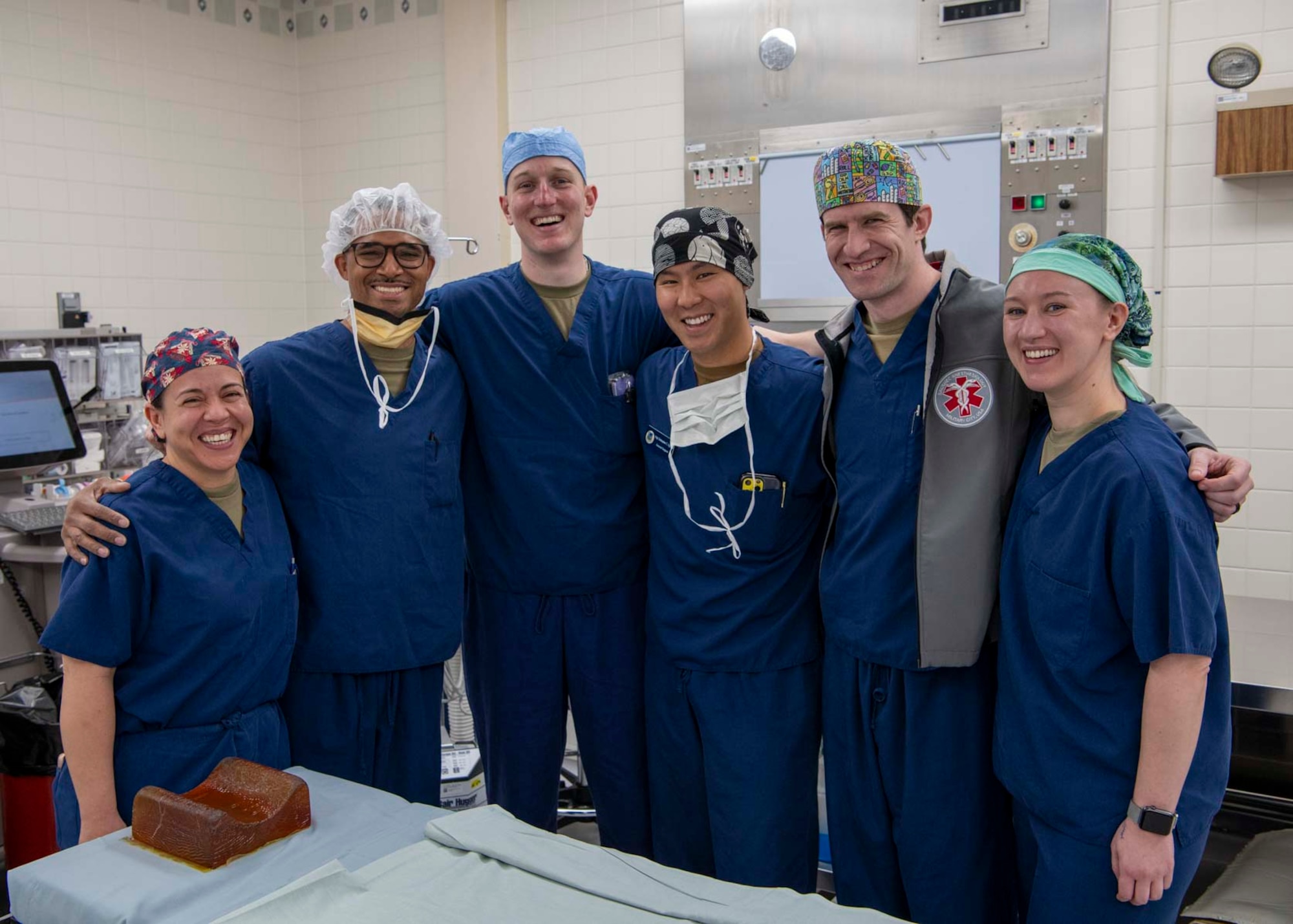 A group of medical staff pose for a photo together in an operating room.