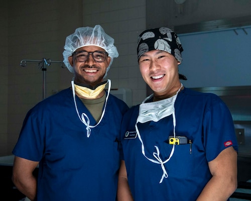 Two surgeons pose for a photo together in an operating room.