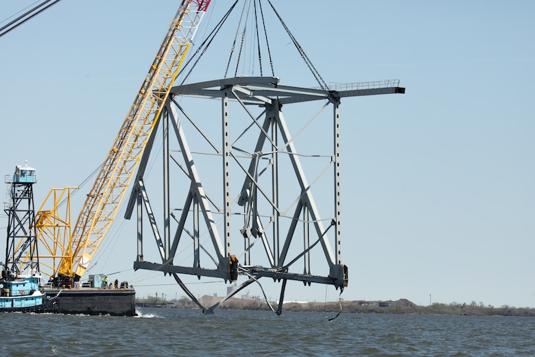 A large floating crane lifts a giant truss of the fallen bridge out of the water.