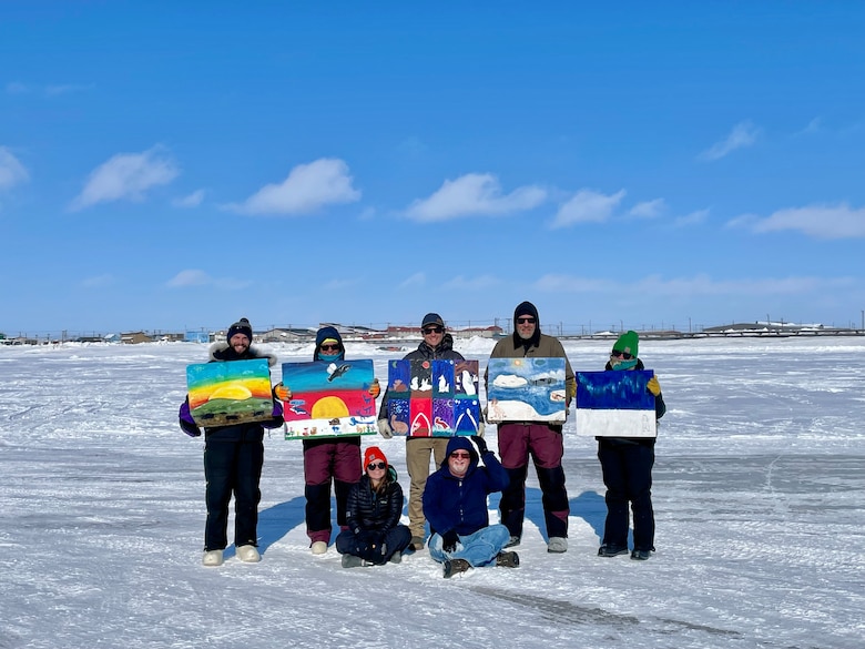 Researchers from ERDC’s Cold Regions Research and Engineering Laboratory and the Coastal and Hydraulics Laboratory hold paintings made by students from Fred Ipalook Elementary School in Utqiagvik, Alaska. The paintings were affixed to the solar panel array by the Joint Integrated Support for Operations in Polar Seas project team
