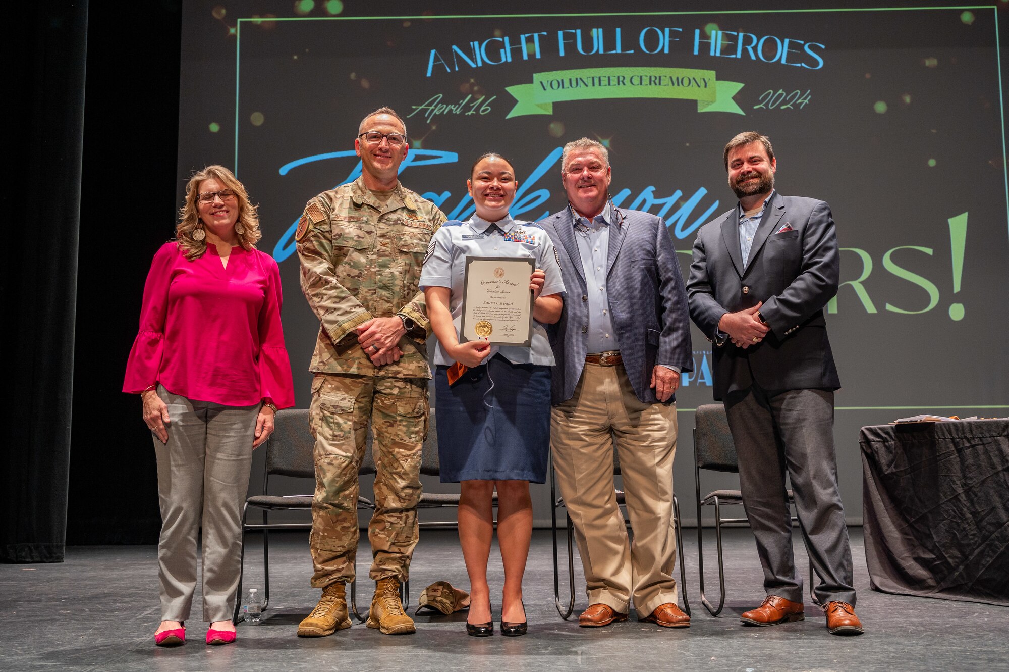 U.S. Air Force Col. Steven Bofferding, 4th Fighter Wing deputy commander, and Goldsboro city local leaders award Senior Airman Laura Carbajal-Nededog, 4th Operational Support Squadron mission planning cell readiness analyst, with the Governor's Award for volunteer service during a volunteer award ceremony at the Paramount Theatre in Goldsboro, North Carolina, April 16, 2024. Due to absence, her award was received by SSgt. Pauline Tukumoeatu, 336th Fighter Squadron non-commissioned officer in charge of intel. Local volunteers convened at the Paramount Theatre for “A Night Full of Heroes Volunteer Ceremony” where they were celebrated and honored by the United Way of Wayne County. (U.S. Air Force photo by Airman 1st Class Leighton Lucero)