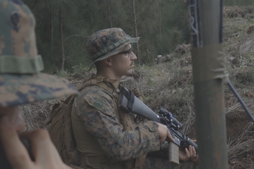 A Marine with a weapon stands watch during an exercise.