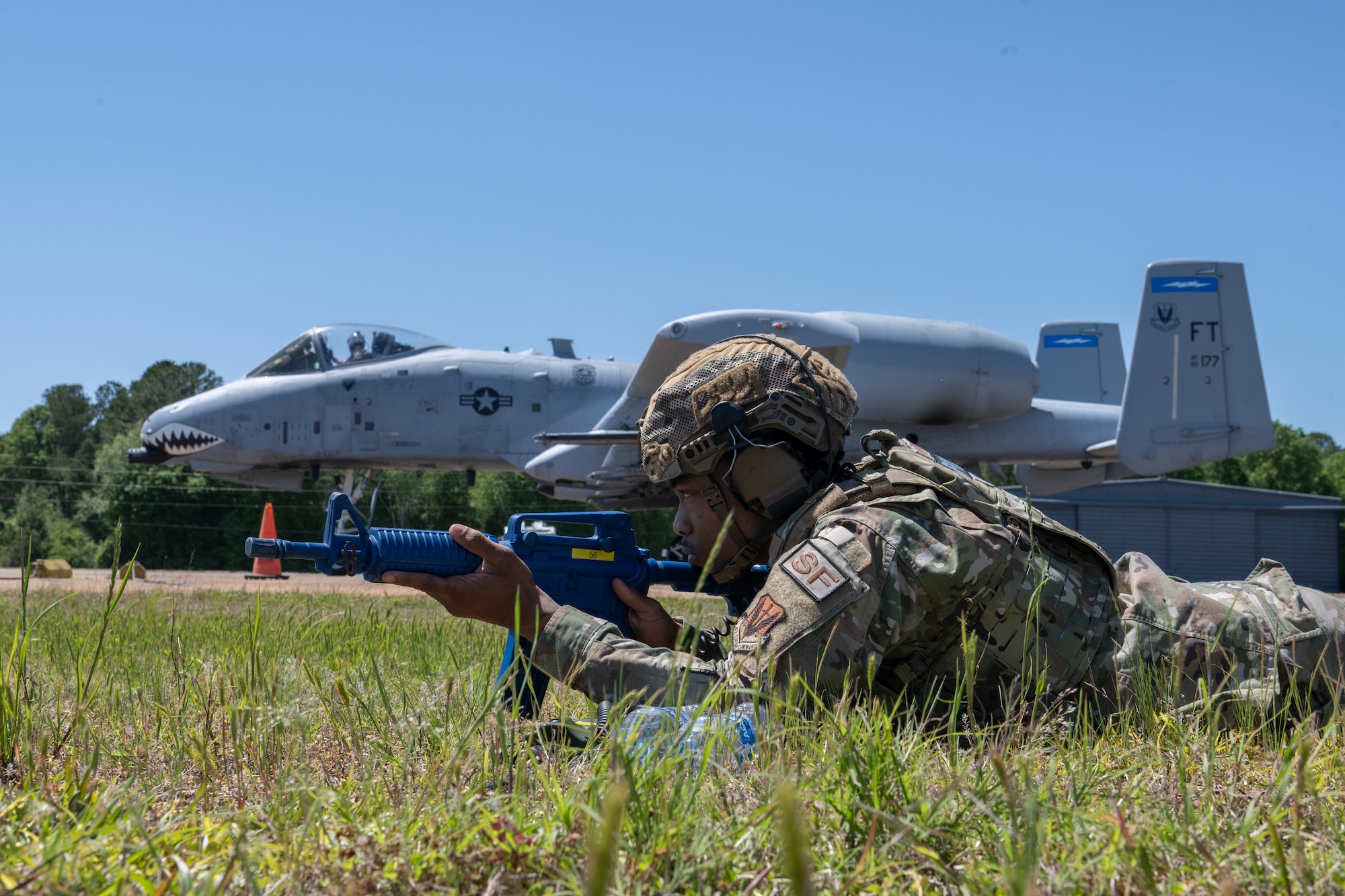 Person laying in fore ground with A-10C Thunderbolt II in the background.