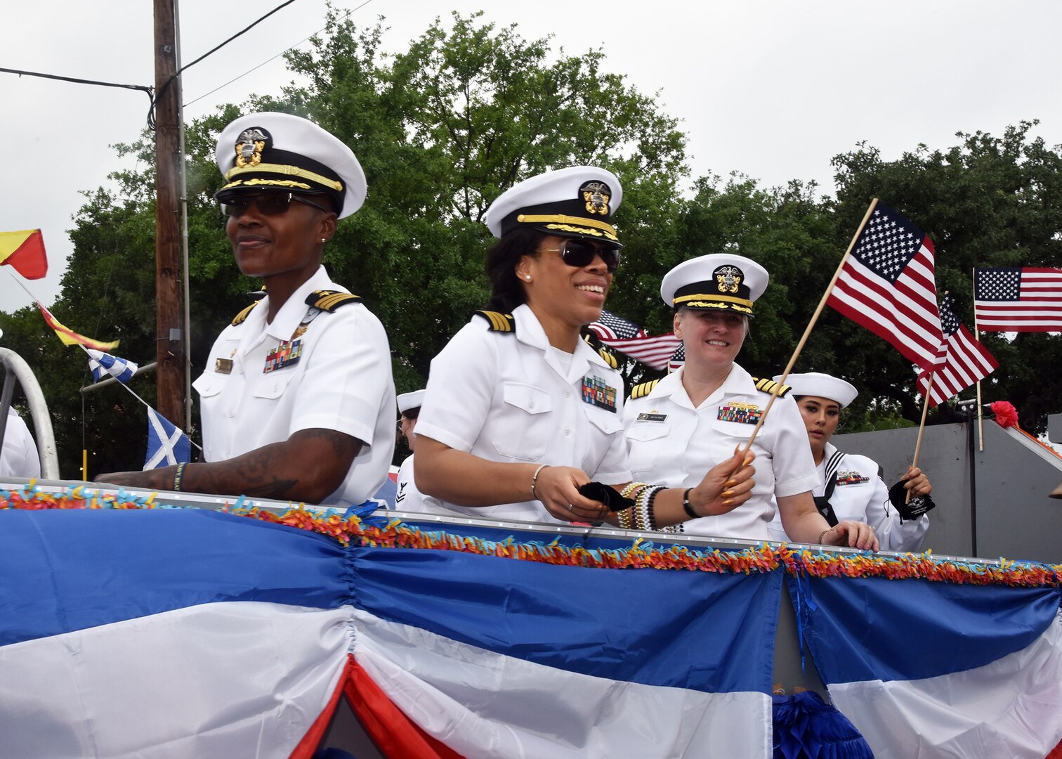 SAN ANTONIO - (April 26, 2024) – Left to right:  Cmdr. Stacey O’Neal, commanding officer, Navy Talent Acquisition Group (NTAG) San Antonio; Cmdr. Nneoma Lewis (Nurse Corps), Non-medical medical case manager, Navy Wounded Warrior (NWW) Program, Navy Region Southeast; and Capt. Jennifer Buechel (Nurse Corps), commanding officer, Naval Medical Research Unit (NAMRU) San Antonio, participated in the Battle of Flowers Parade held during Fiesta San Antonio. The Battle of Flowers Parade is the oldest event and largest parade of Fiesta San Antonio attracting crowds of more than 350,000. Leading the Sailors in the parade was Rear Adm. Walter Brafford, commander, Naval Medical Forces Support Command (NMFSC). Joint Base San Antonio is proud to be part of the diverse and vibrant community of San Antonio also known as Military City USA. (U.S. Navy Photo by Burrell Parmer, Naval Medical Research Unit San Antonio Public Affairs/Released)