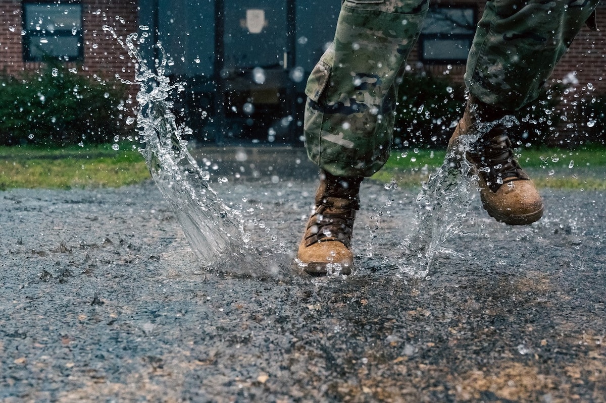 An Airman splashes through a flooded parking lot during a downpour at Joint Base Langley-Eustis, Virginia, March 6, 2024. Multiple areas around the instillation are prone to flooding during heavy rains due to the areas being below sea level. (U.S. Air Force photo by Airman 1st Class Ian Sullens)