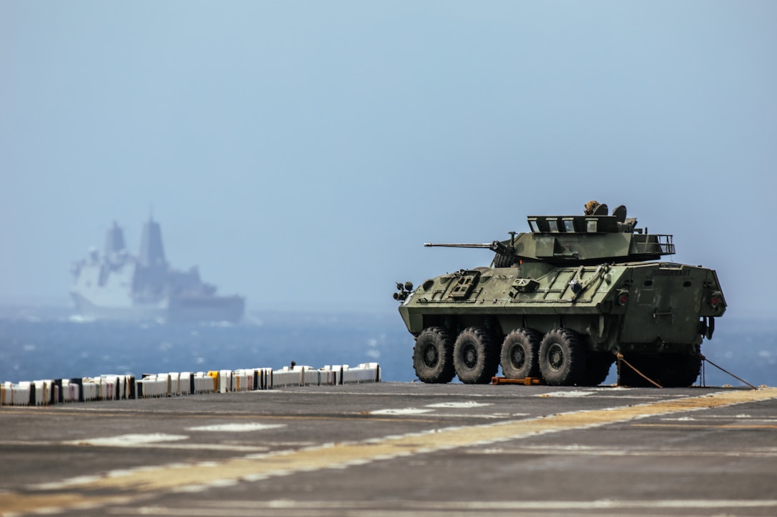 U.S. Marines with Battalion Landing Team 1/8, 24th Marine Expeditionary Unit (MEU), set up a defense of amphibious task force posture with a Light Armored Vehicle on the flight deck of the USS Wasp (LHD 1) while the Wasp (WSP) Amphibious Ready Group (ARG) conducts a simulated strait transit during Composite Training Unit Exercise (COMPTUEX) in the Atlantic Ocean, April 26, 2024. The 24th MEU and Wasp (WSP) Amphibious Ready Group (ARG) are conducting COMPTUEX, their final at-sea certification exercise under the evaluation of Carrier Strike Group 4 and Expeditionary Operations Training Group. Throughout COMPTUEX, the WSP ARG-24th MEU is evaluated across a spectrum of scenarios that determine their readiness to deploy. (U.S. Marine Corps photo by Gunnery Sgt. Hector de Jesus)