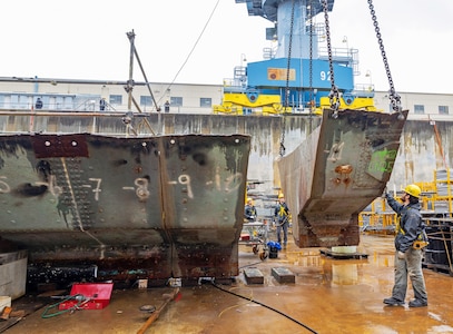 A team of riggers from Code 740, Riggers, help guide a section of concrete ballast from old Caisson 3's keel as it's lifted by crane, March 27, 2024, up and out of Dry Dock 3 at Puget Sound Naval Shipyard & Intermediate Maintenance Facility in Bremerton, Washington. (U.S Navy photo by Wendy Hallmark)