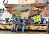 A team of riggers from Code 740, Riggers, help lower a section of concrete ballast from old Caisson 3's keel onto a railroad car, March 27, 2024, after lifting up and out of Dry Dock 3 at Puget Sound Naval Shipyard & Intermediate Maintenance Facility in Bremerton, Washington. The sections of caisson are being transported for recycling. (U.S Navy photos by Wendy Hallmark).