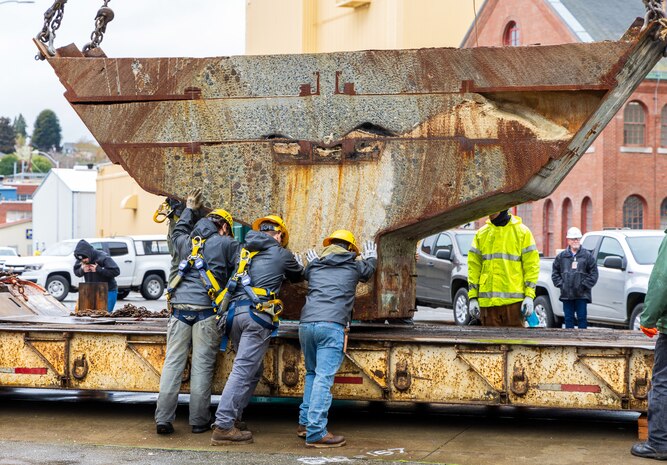 A team of riggers from Code 740, Riggers, help lower a section of concrete ballast from old Caisson 3's keel onto a railroad car, March 27, 2024, after lifting up and out of Dry Dock 3 at Puget Sound Naval Shipyard & Intermediate Maintenance Facility in Bremerton, Washington. The sections of caisson are being transported for recycling. (U.S Navy photos by Wendy Hallmark).