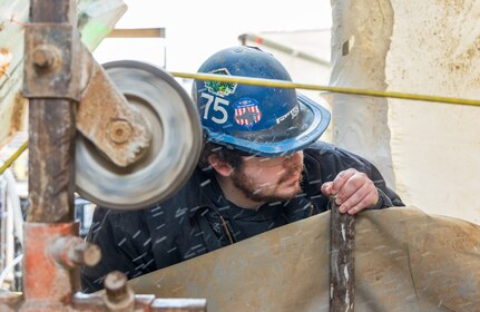 Chase Evans, general worker, Shop 75, IRR Ship Dismantling, checks the tension of the pulleys on the wire saw used for cold-cutting through the steel and concrete ballast of old Caisson 3's keel March 20, 2024, at Puget Sound Naval Shipyard & Intermediate Maintenance Facility in Bremerton, Washington. (U.S Navy photos by Wendy Hallmark).