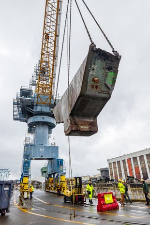 A team of riggers from Code 740, Riggers, help guide a section of concrete ballast from old Caisson 3's keel as it's lifted by crane, March 27, 2024, up and out of Dry Dock 3 at Puget Sound Naval Shipyard & Intermediate Maintenance Facility in Bremerton, Washington. (U.S Navy photos by Wendy Hallmark)